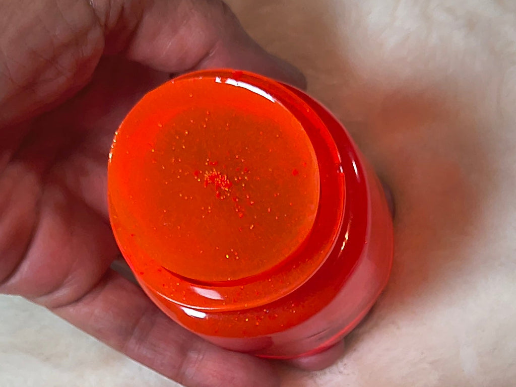 Cute close up of little neon orange bottle with stopper.